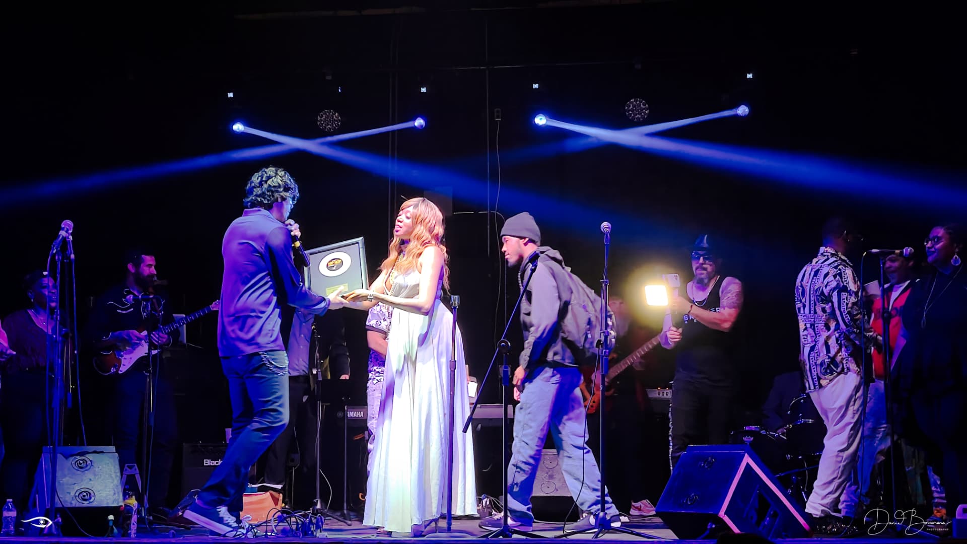 Performers on stage under blue concert lighting during a United GA Entertainment live production.